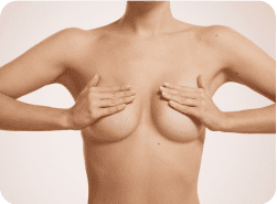 A woman is holding her breast up with both hands.